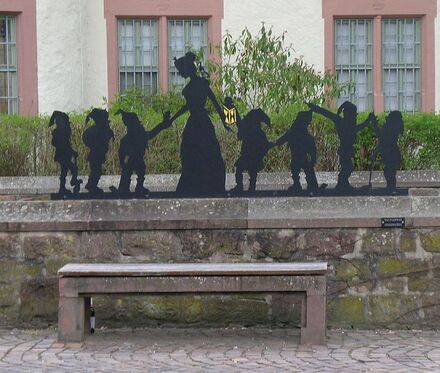 A black silhouette sculpture of Snow White surrounded by the seven dwarves.